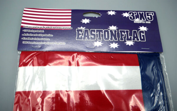 Detail photo of a packaged Easton PA cloth flag, with this information on the label: "3' x 5', Rough Tex 100D, 4 Rows sewing on fly side & real brass grammets, UV block protected, Anti rain and acid protection, Excellent wind resistance, 100D Premium oxford polyester flag fabric."